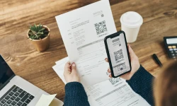 Woman paying invoice scanning QR code from document using fast secure payment system and smartphone QR scanner. Business woman p